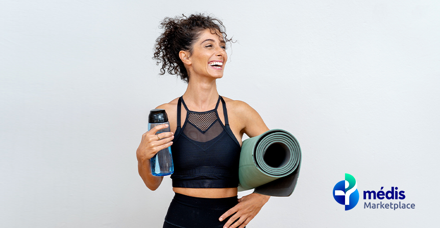 Senhora feliz a segurar garrafa de água e colchão de exercício